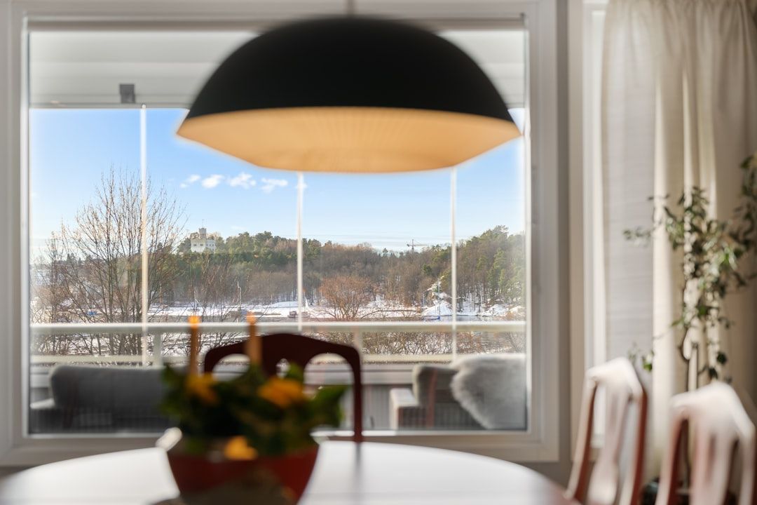 Vintervy genom fönster från ett dukat matsalsbord med stämningsfull belysning.