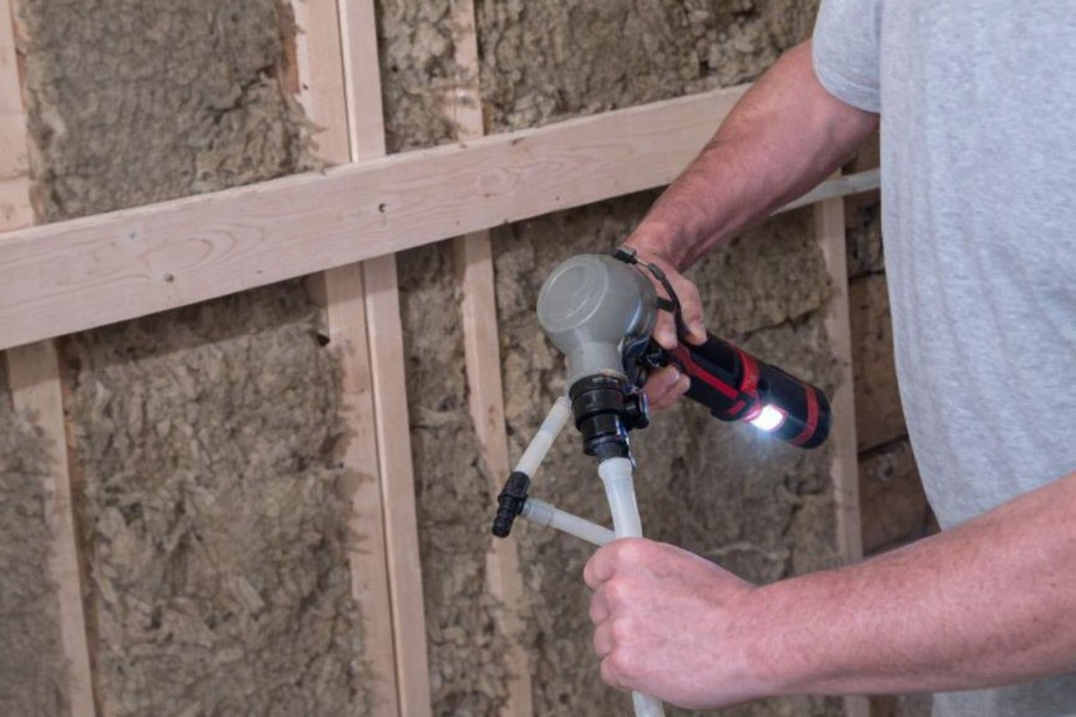 En hantverkare använder ett specialverktyg vid isolering av en vägg under renovering.